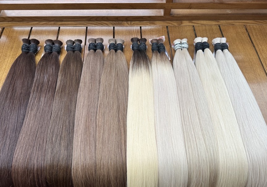 VNEXHAIR Farbpalette – Echthaar-Extensions von Dunkelbraun bis Platinblond auf Holztisch